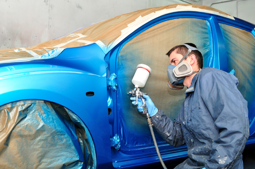 Painter working with blue car.